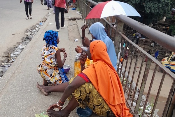 Des mendiants nigériens sollicitent les passants sur un pont d’Abidjan, illustrant un phénomène croissant.
