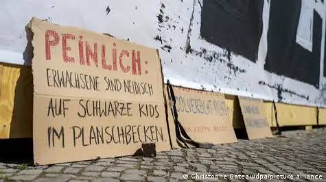Des pancartes contre le racisme et en soutien à la Volksbühne. Sur l'une d'elles on peut lire : "Quelle honte! Des adultes sont jaloux d'enfants noirs dans une pataugeoire"